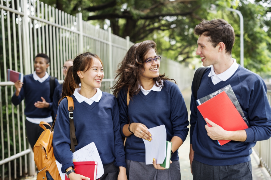 Three pupils walking in a line smiling at each other